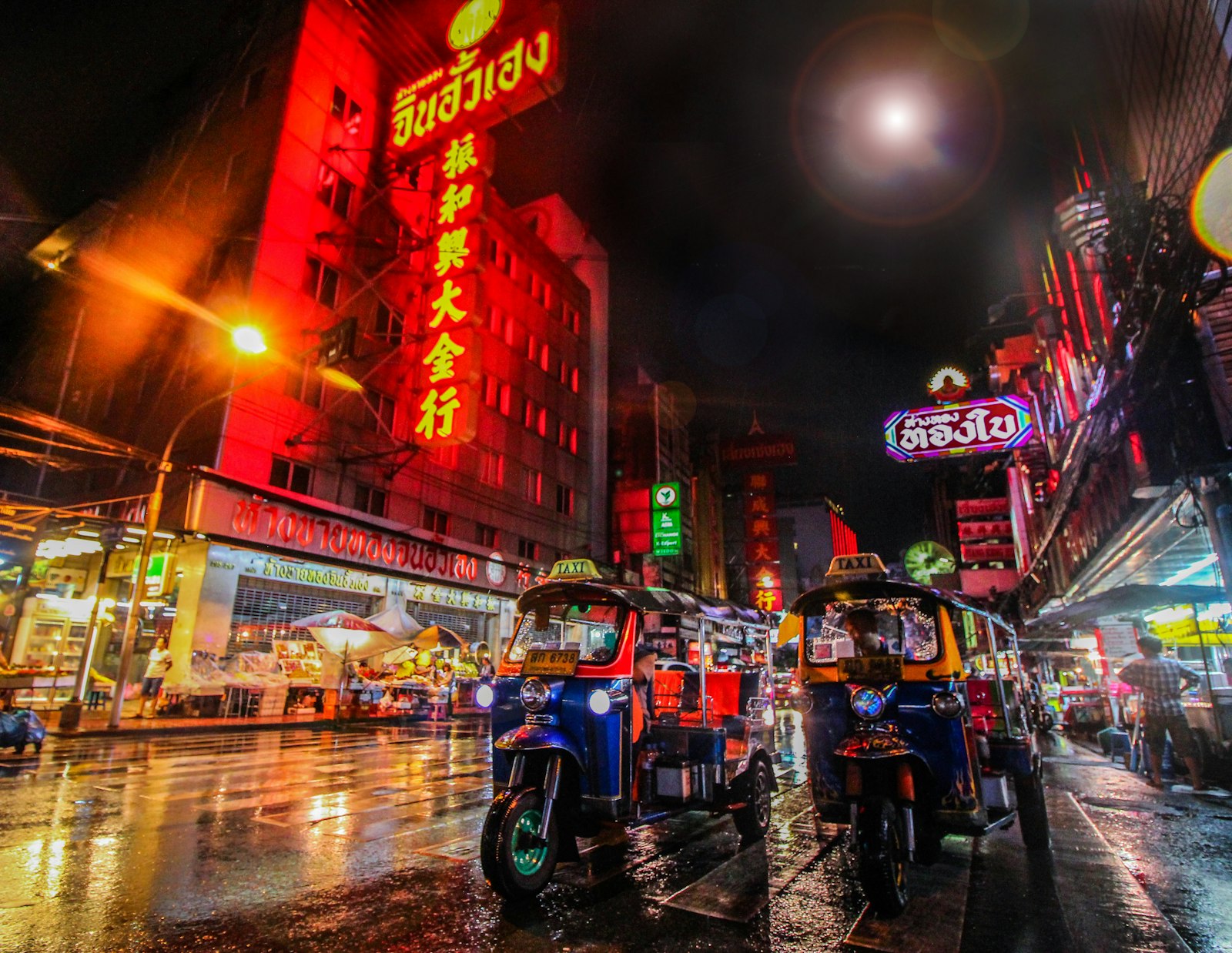 Illustrative photo: tuk-tuks on a neon-lit Bangkok street at night