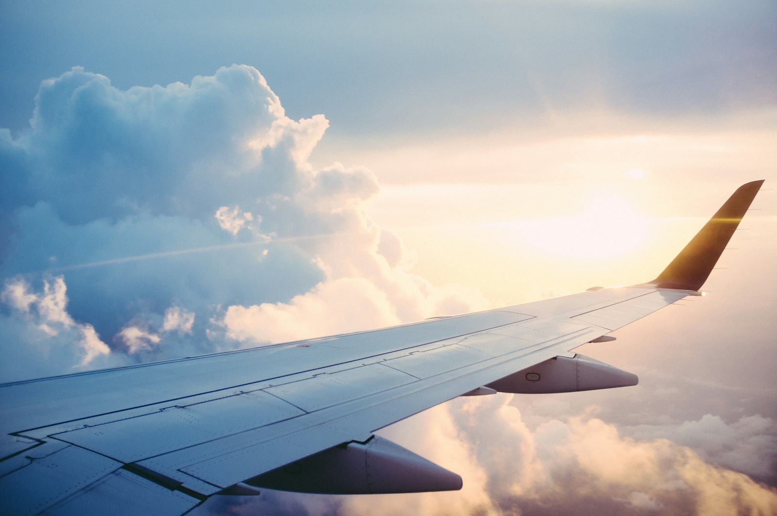 Illustrative photo: an aircraft wing above the clouds at sunset
